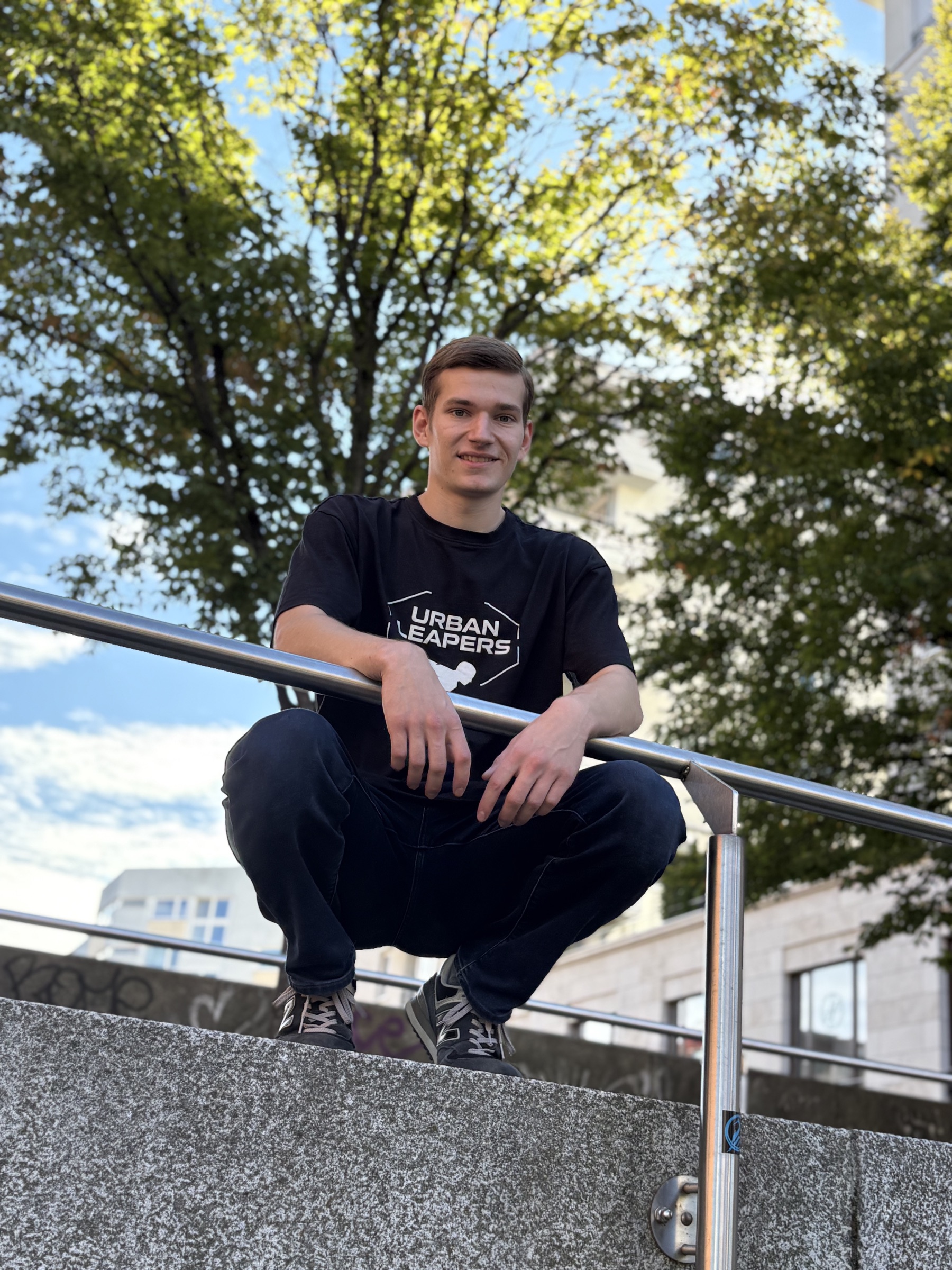 Jonathan Schmakies sitzt im Freien auf einer Parkour-Stange.
